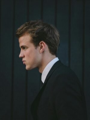 Side view of young handsome man in classic suit near black wooden wall on street